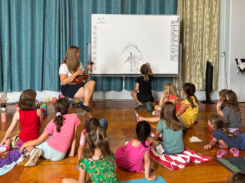 Group of young girls drawing pictures on whiteboard